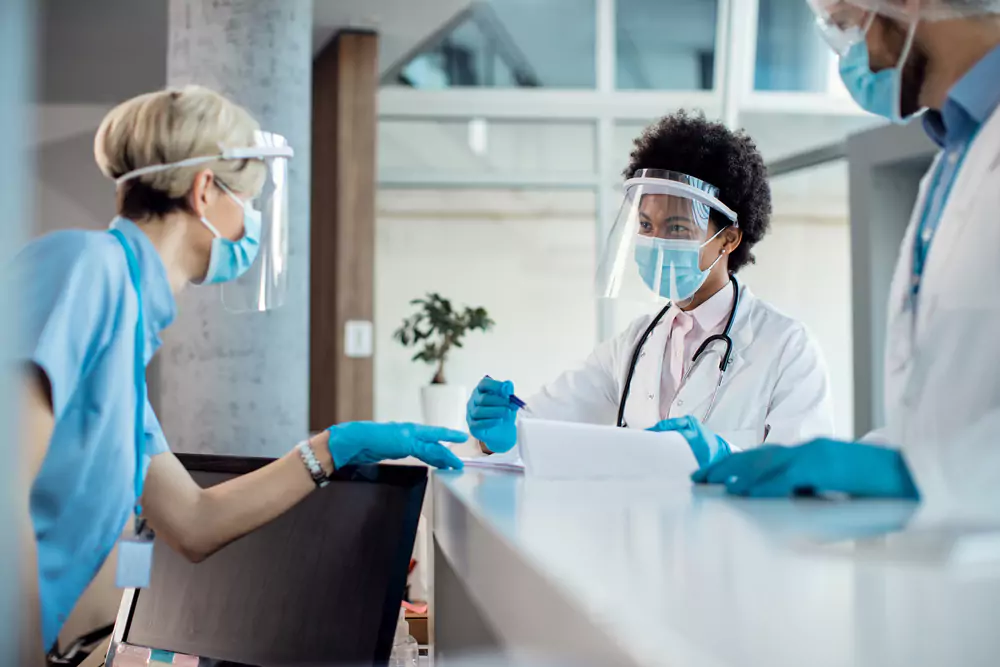 Doctor Talking Nurse While Writing Medical Data