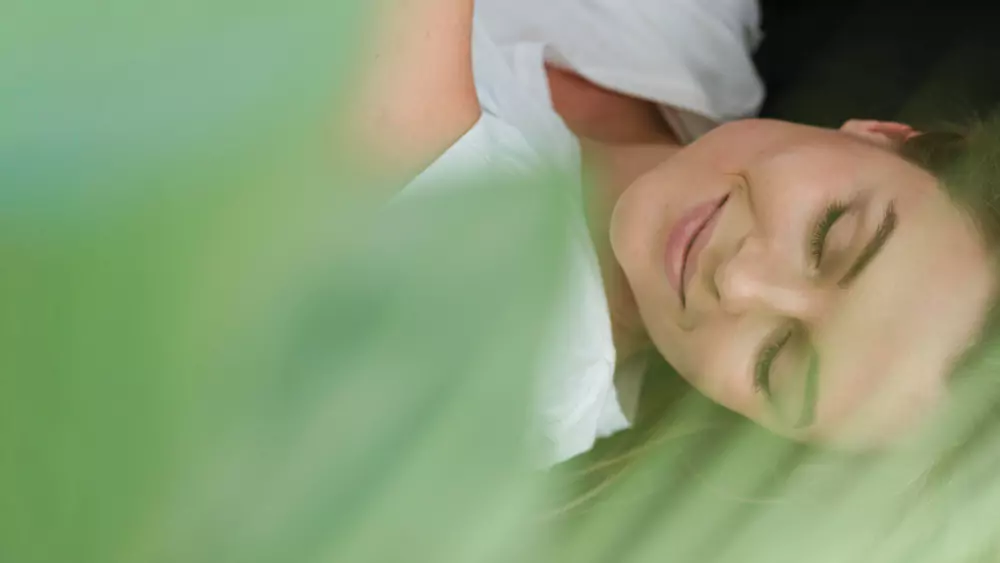 Woman With Closed Eyes And Blurred Plant